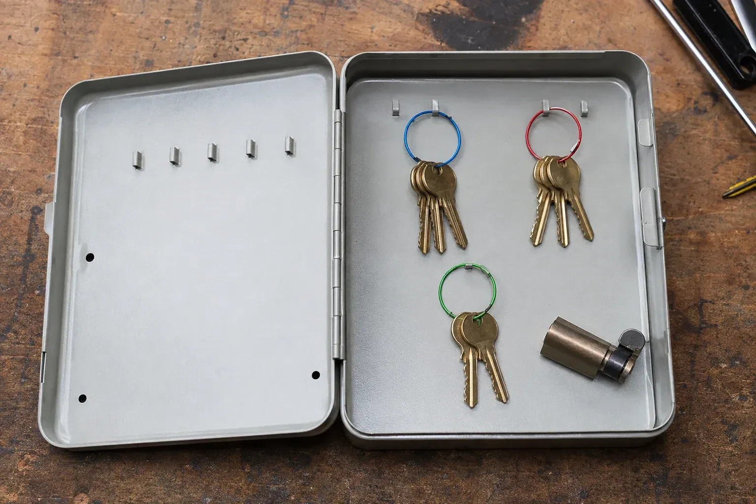 Three groups of keys on colored rings in an open metal key cabinet. — Master Key System Design, Mississauga